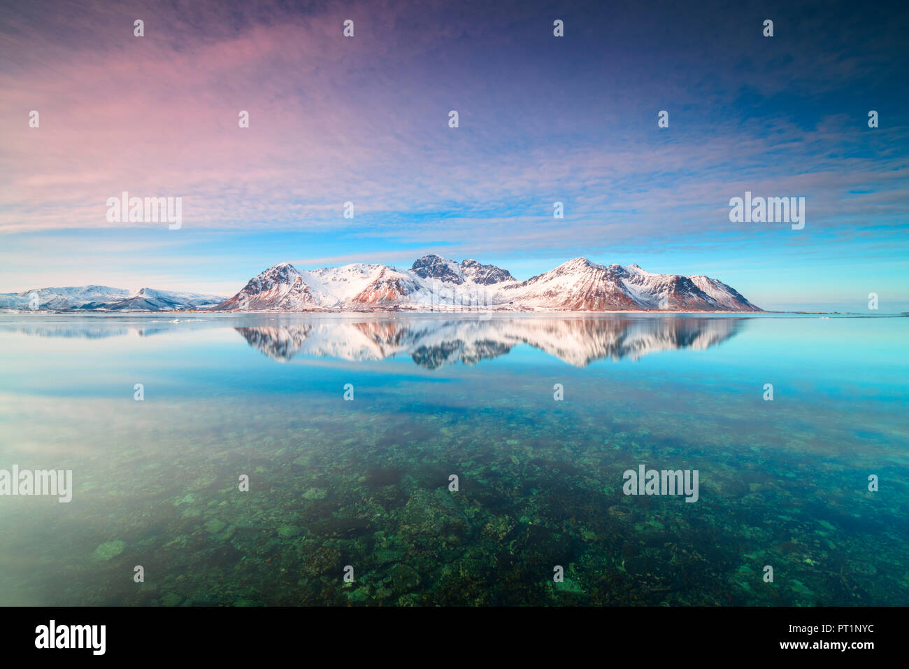 Vette innevate si riflette nel mare cristallino, Grundstad, Isole Lofoten in Norvegia Foto Stock