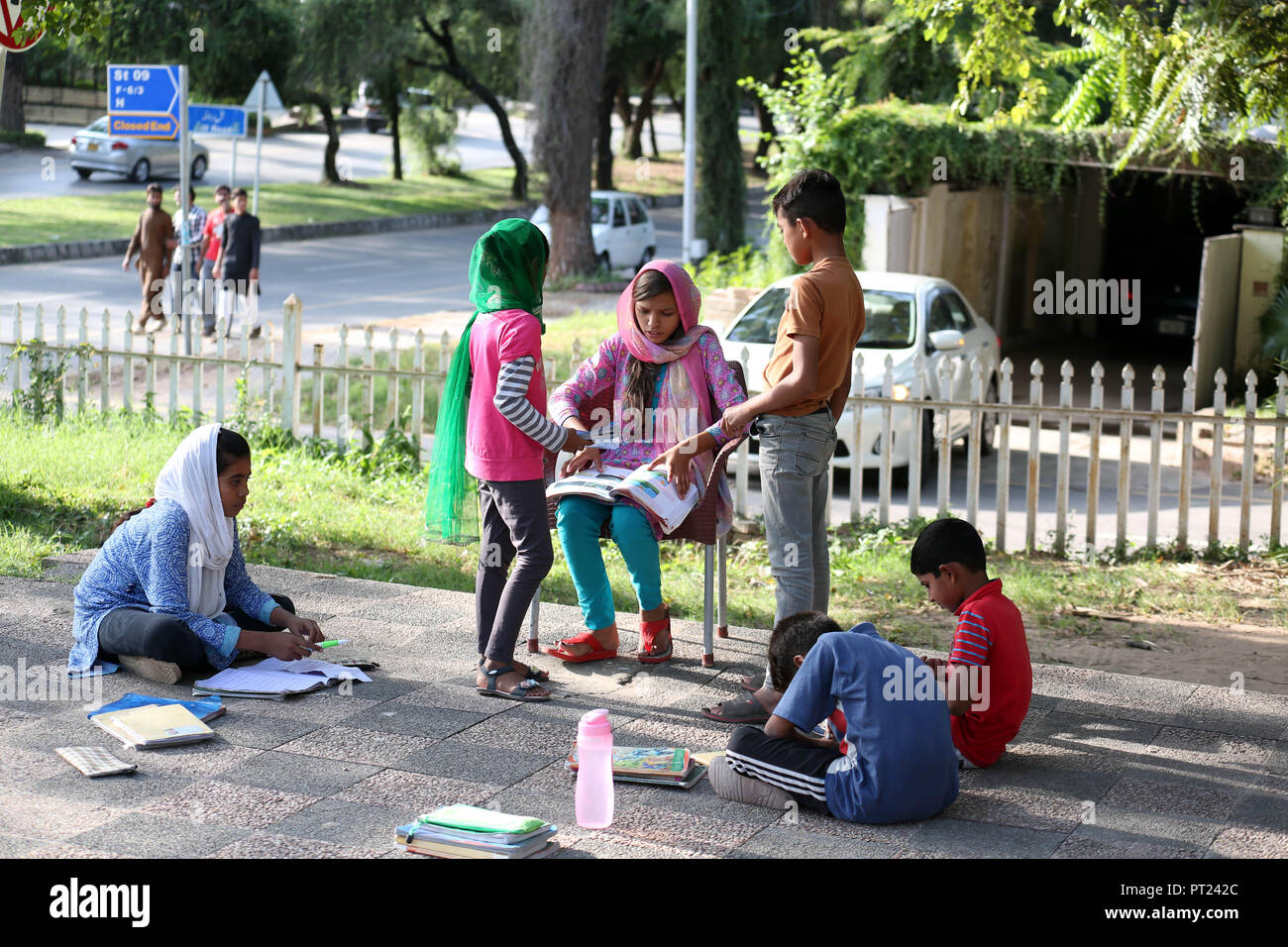 Islamabad, Pakistan. 5 Ottobre, 2018. Un insegnante controlla il lavoro dei suoi studenti di una scuola di fortuna istituito in un parco pubblico a Islamabad, la capitale del Pakistan, il 5 ottobre, 2018. Il mondo degli insegnanti di giorno è osservato su 5 Ottobre. Credito: Ahmad Kamal/Xinhua/Alamy Live News Foto Stock