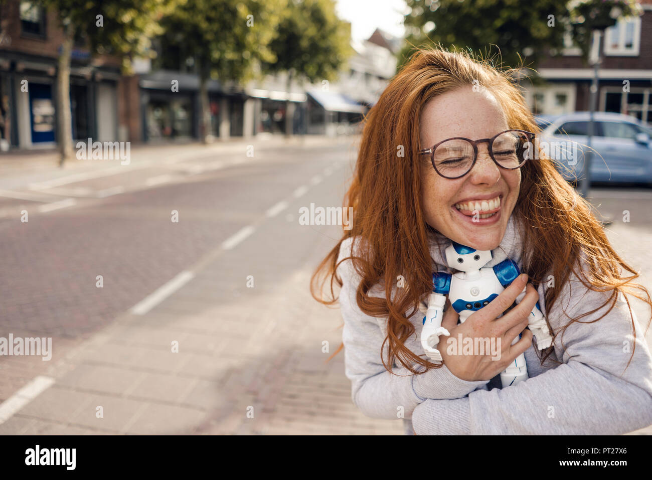 Redheaded donna abbracciando robot giocattolo Foto Stock