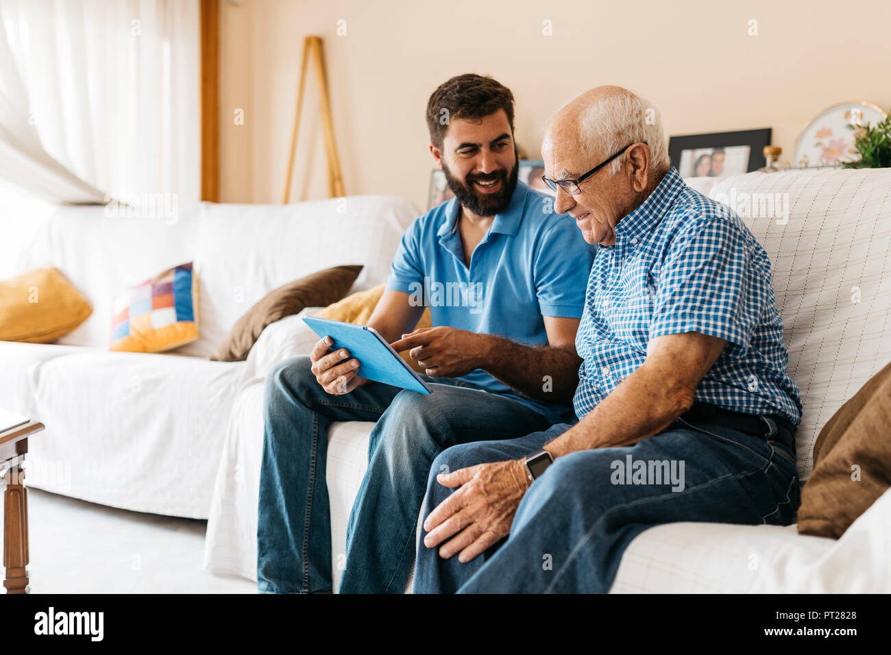 Nipote di adulti insegnamento il nonno di utilizzare tablet Foto Stock