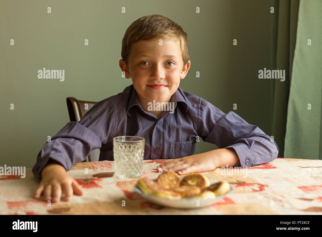 Ragazzo sorridente seduti ad un tavolo con la cheesecake Foto Stock
