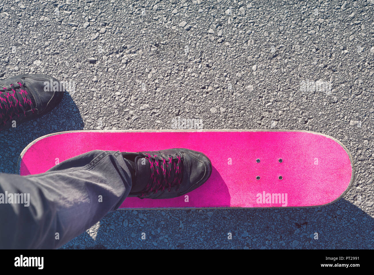 Pattinatore piedi su skateboard rosa Foto Stock