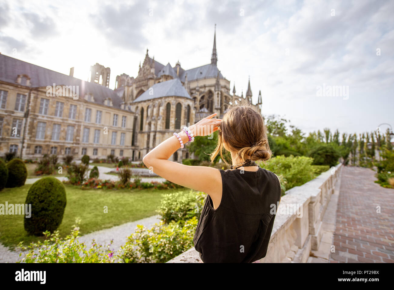 Giovane donna godendo di una splendida vista sulla cattedrale di Reims e giardini in viaggio nella città di Reims, Francia Foto Stock