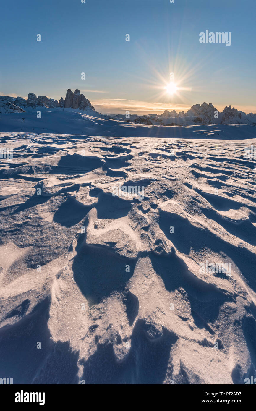 Prato Piazza / Prato Piazza, Dolomiti, provincia di Bolzano, Alto Adige, Italia, Patterns in wind-eroso neve sullo sfondo il Rising Sun e le famose cime delle Tre Cime di Lavaredo Foto Stock