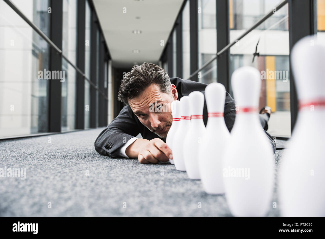 Diligente manager sdraiato sul pavimento in ufficio di passaggio dei perni di regolazione Foto Stock