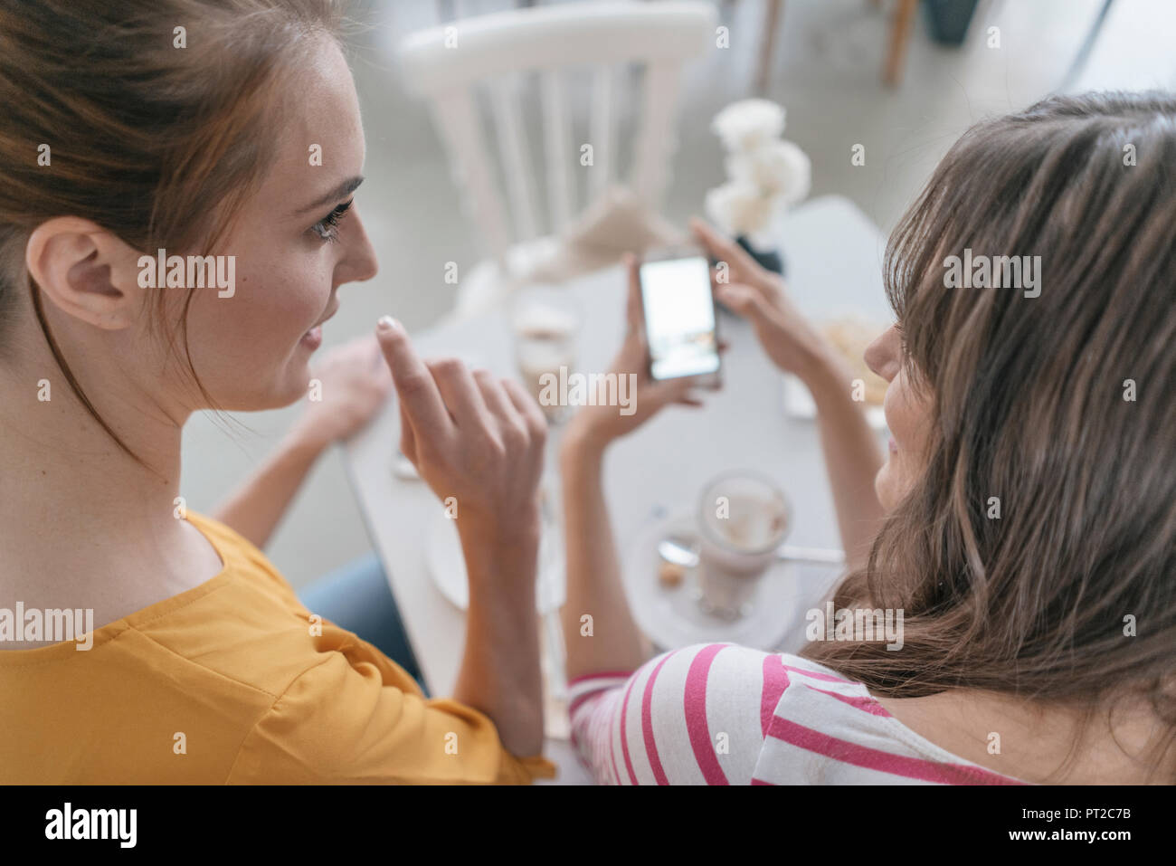 Due amiche riuniti in un coffee shop, utilizza lo smartphone Foto Stock