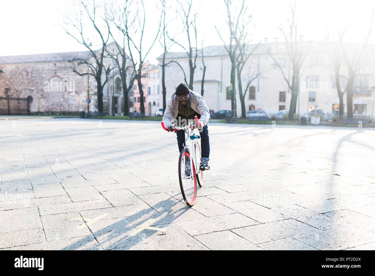 Giovane uomo Bicicletta Equitazione su piazza urbana Foto Stock