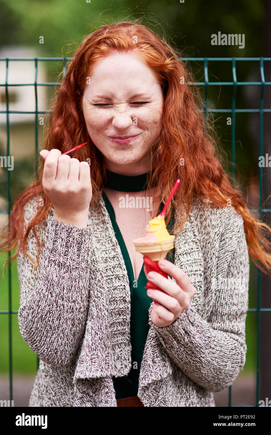 Ritratto di freckled redheaded donna mangiare gelato Foto Stock