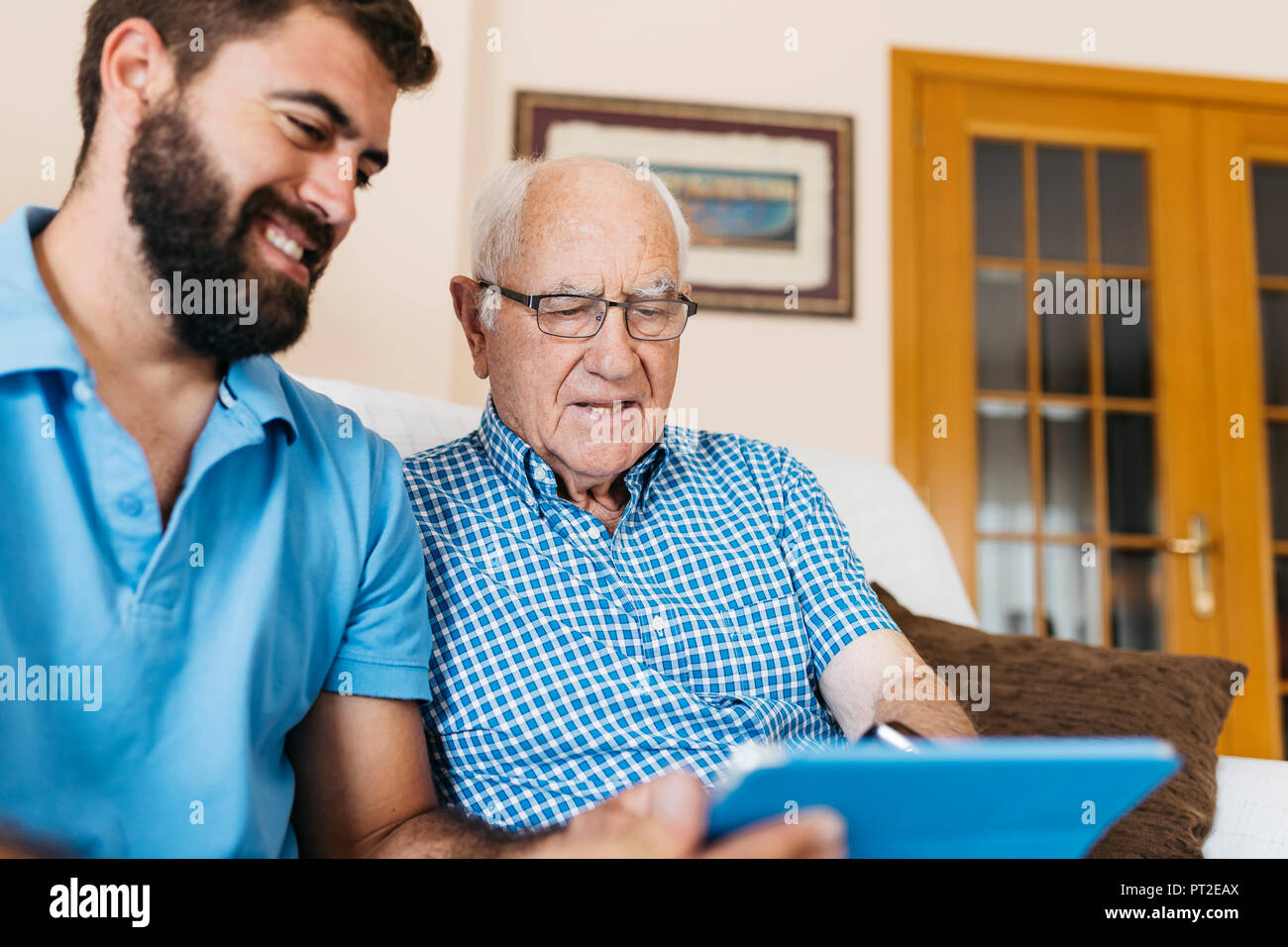 Nipote di adulti insegnamento il nonno di utilizzare tablet Foto Stock