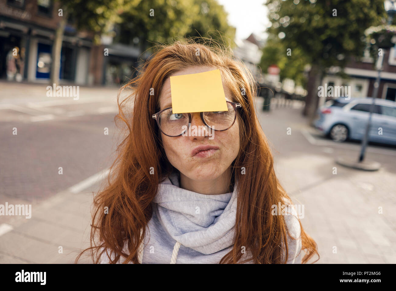 Redheaded donna con adesivo nota grippaggio sulla sua fronte Foto Stock