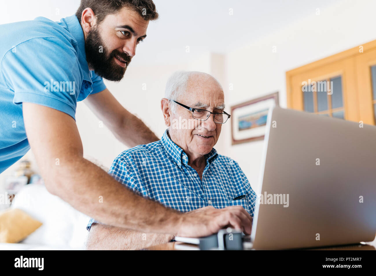 Nipote di adulti insegnamento a suo nonno per uso portatile Foto Stock