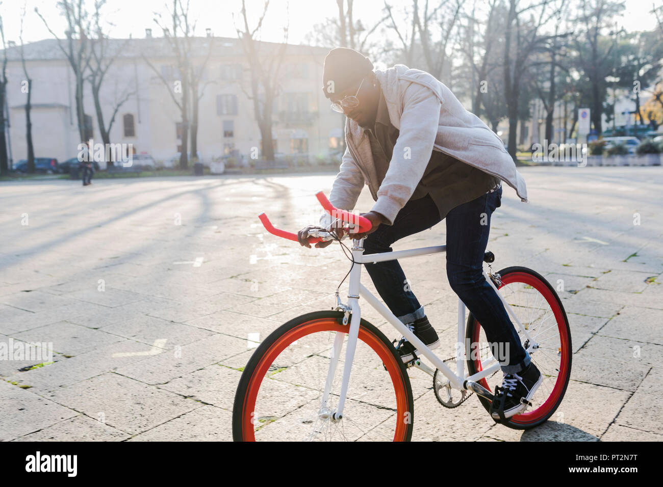 Giovane uomo Bicicletta Equitazione su piazza urbana Foto Stock