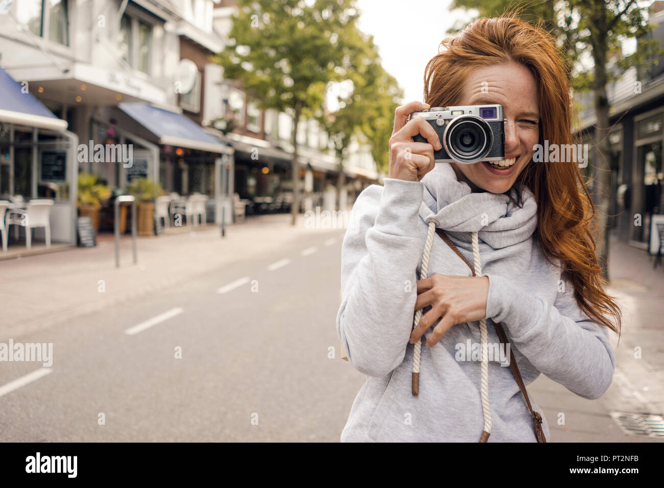 Redheaded donna utilizzando la telecamera analogica Foto Stock