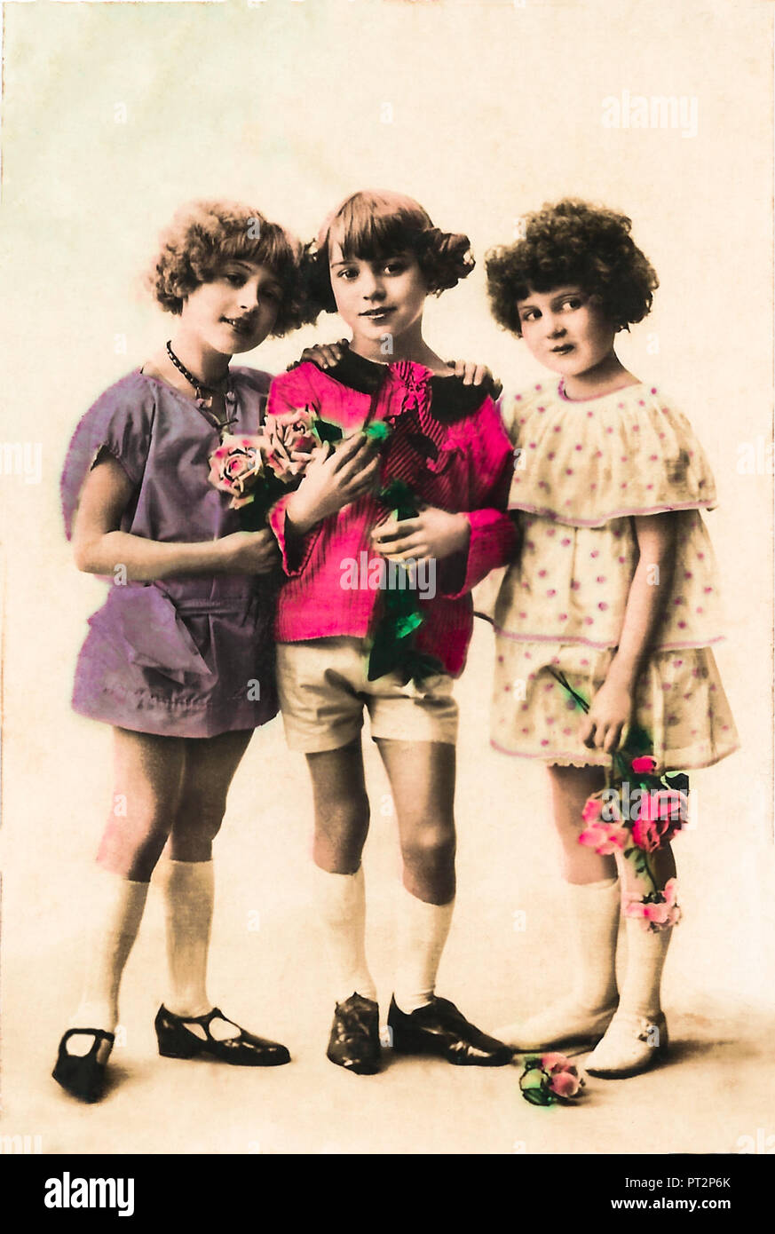 Cheeky Vintage bambine holding fiori, 1910s, cartolina Vintage. Foto Stock