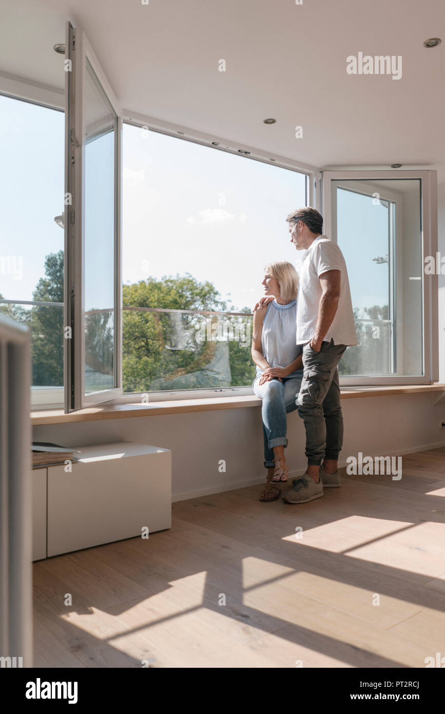 Coppia matura in corrispondenza della finestra nella stanza vuota Foto Stock