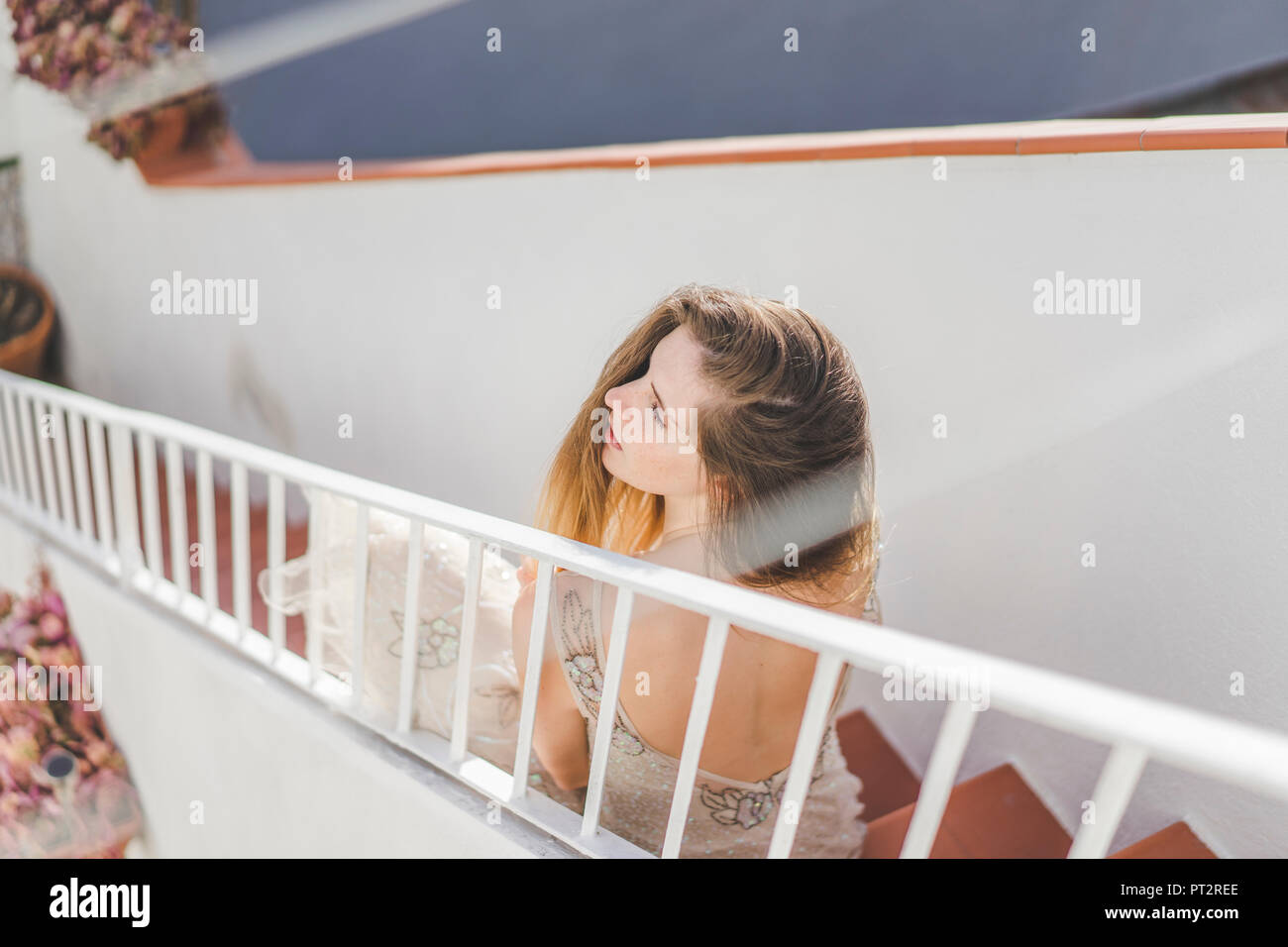 Giovane donna che indossa un abito da sposa, seduti sulle scale Foto Stock