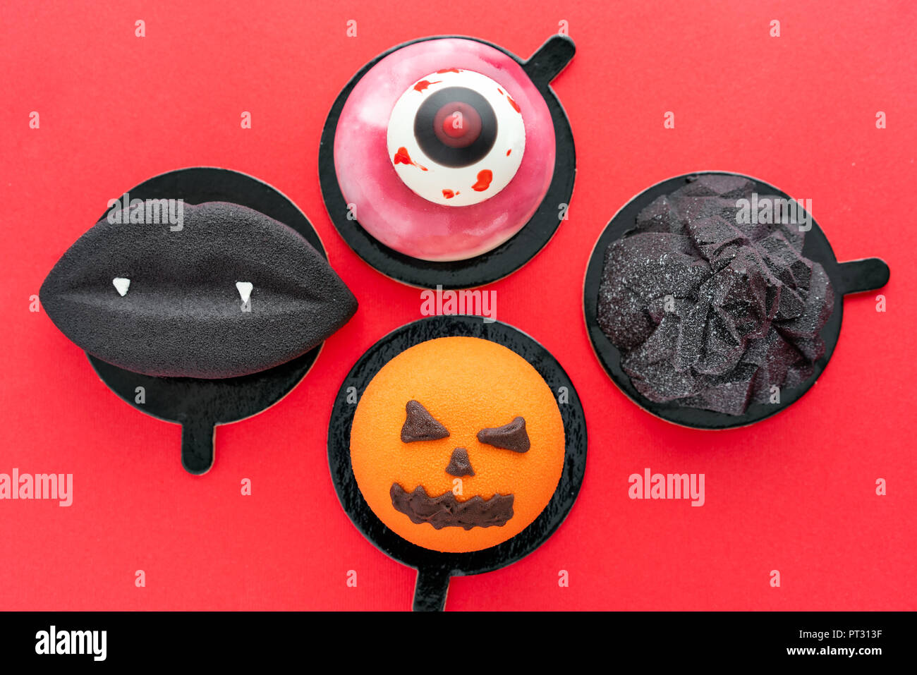 Labbra nere con vampiro canini, strappato un occhio, un infausto di zucca e black mountain. Scary Halloween mousse di zucca su rosso colore di sfondo, vista dall'alto Foto Stock