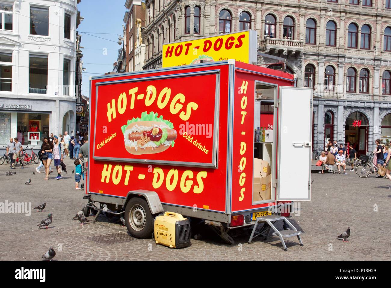 Un rosso chiuso hot dog stand con la porta aperta, circondato da piccioni viaggiatori e turisti in Piazza Dam, Amsterdam, Paesi Bassi Foto Stock
