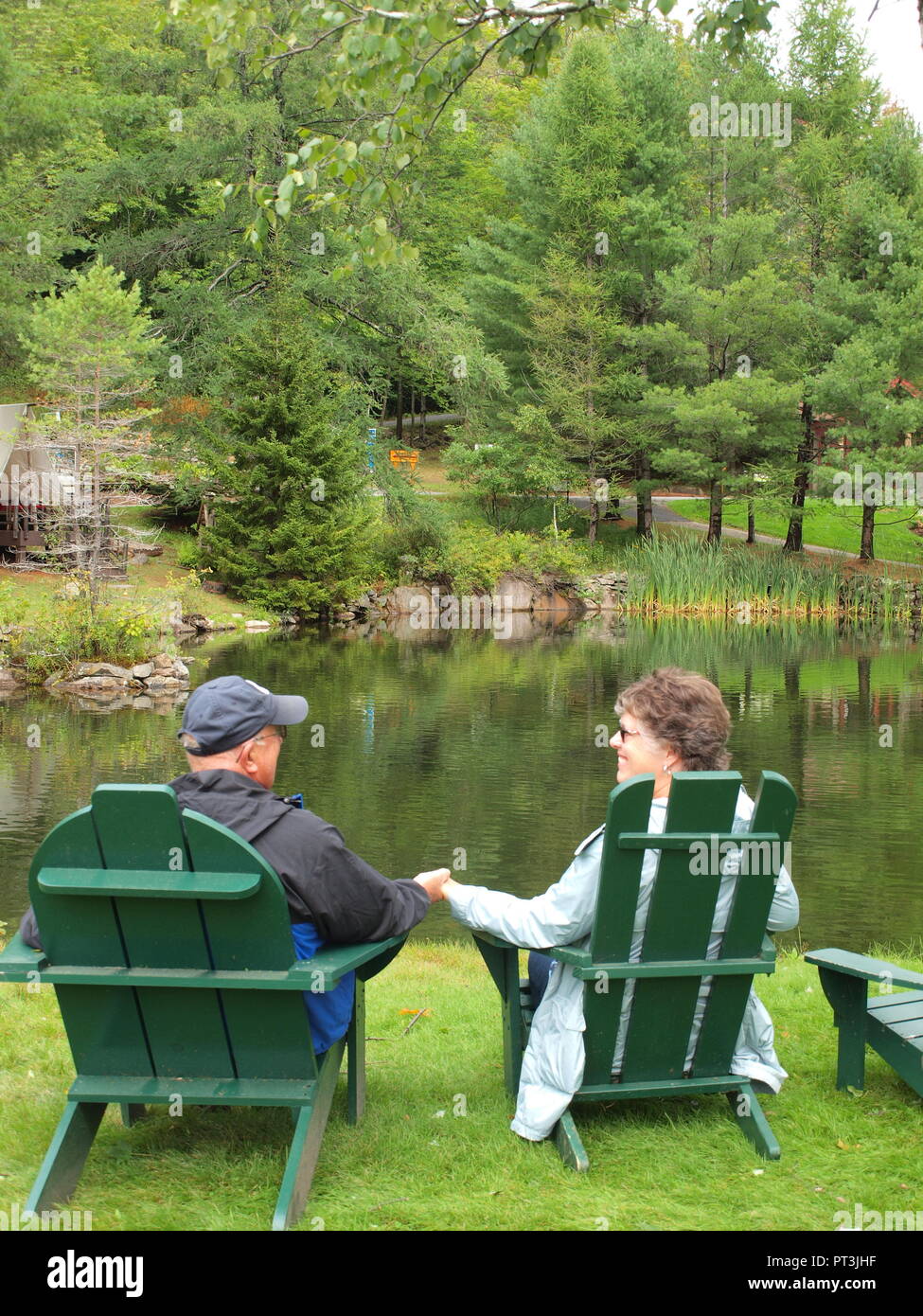 Coppia sposata godendo di azienda in verde sedie Adirondack. Foto Stock