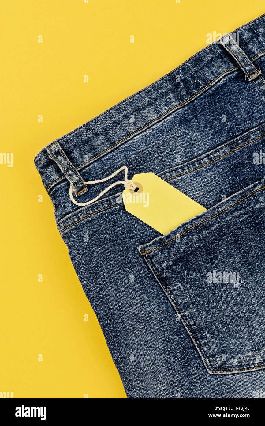 Concetto di vendita Venerdì nero e cyber lunedì sconti tag con jeans blu su sfondo giallo. Spazio di copia, laici piatta Foto Stock