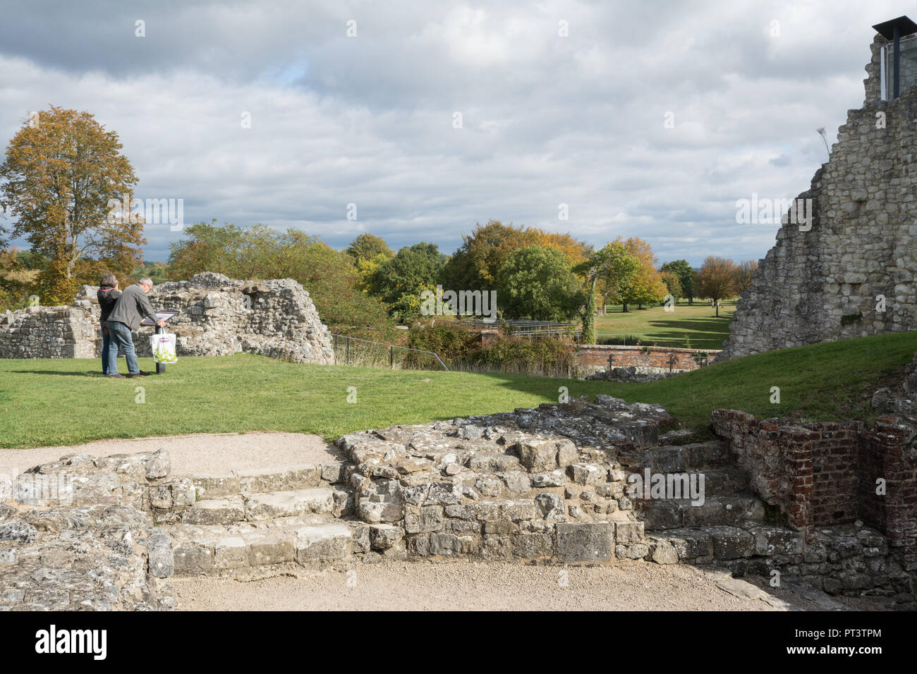 Vista di autunno alberi dai motivi di Farnham Castle Keep, una attrazione turistica nel Surrey, Regno Unito, con visitatori durante la lettura di una scheda informazioni Foto Stock