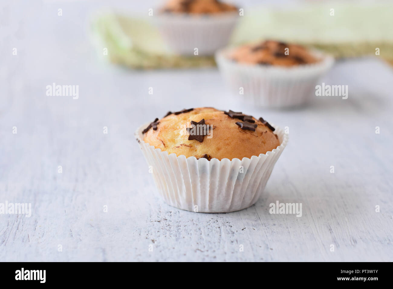 Deliziosi dolci fatti in casa muffin alla vaniglia con scaglie di cioccolato in bianco sullo sfondo di legno Foto Stock