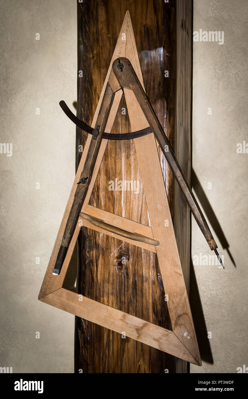 Triangolo di legno e compassi utilizzato in una vecchia scuola, appeso alla parete Foto Stock