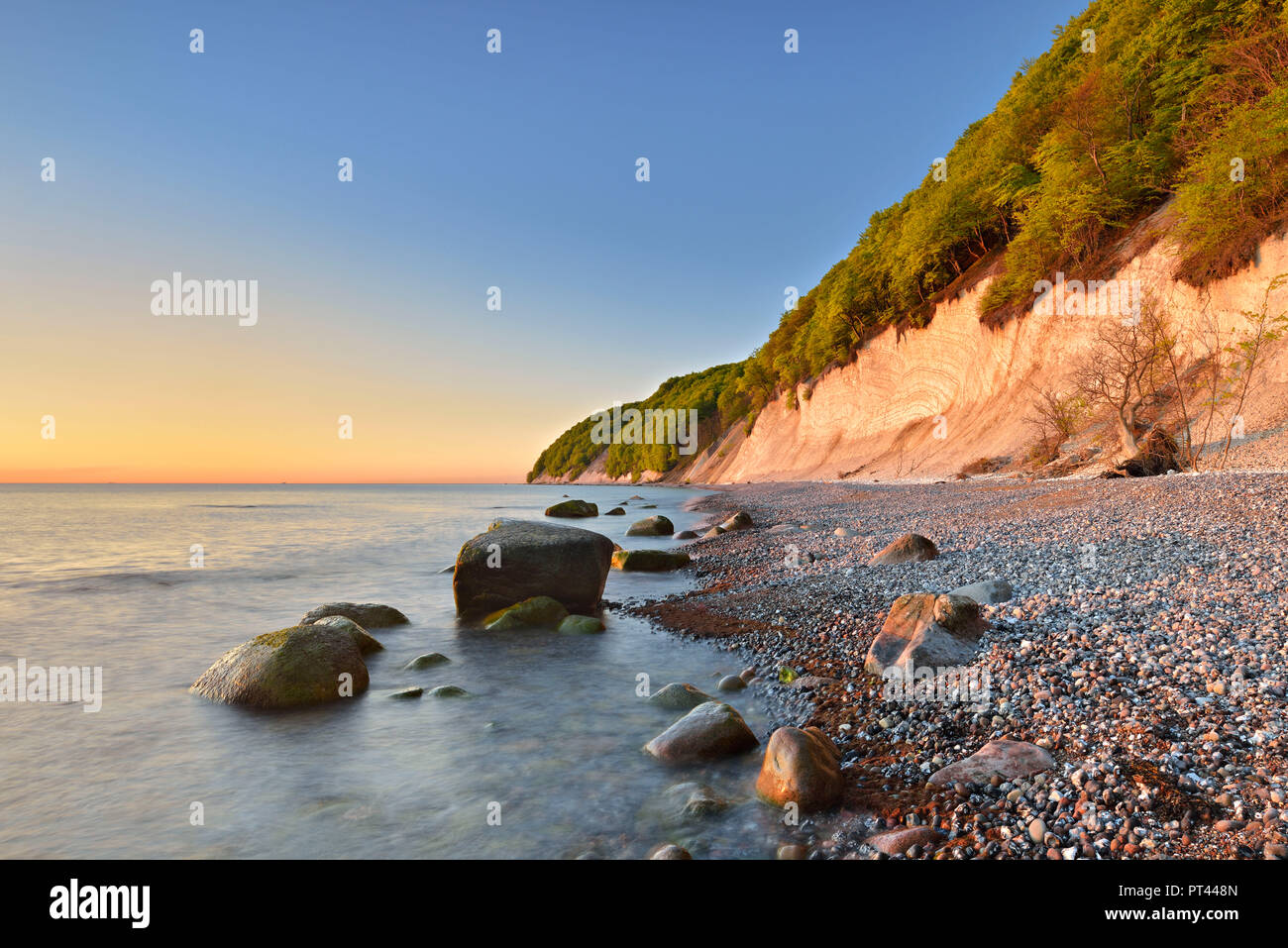 Germania, Meclemburgo-Pomerania, Rügen Isola, Jasmund National Park, chalk cliffs nella luce del mattino, massi su una spiaggia ghiaiosa Foto Stock