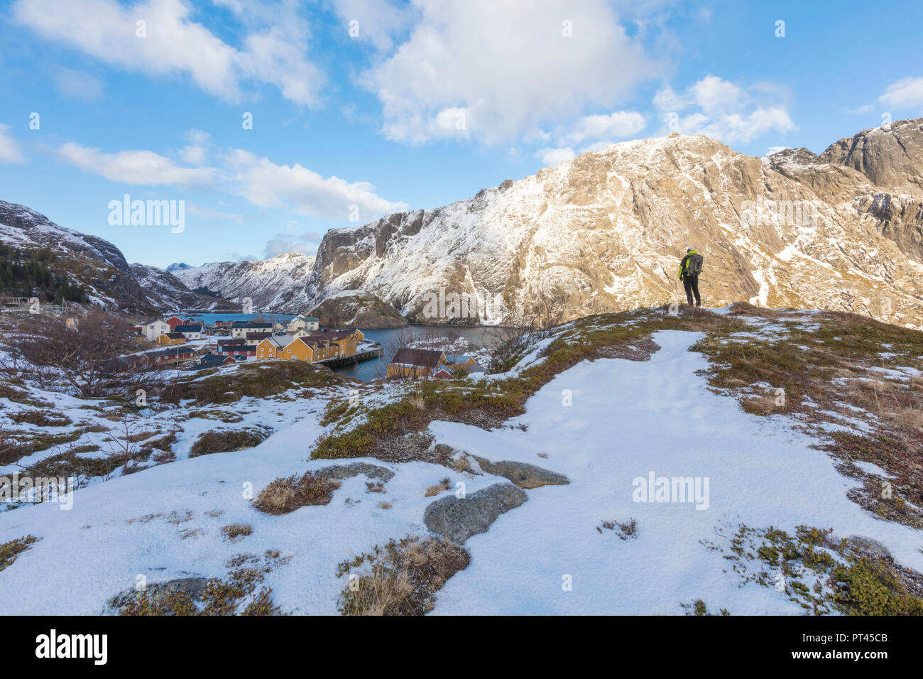 Escursionista sul picco roccioso, Nusfjord, Isole Lofoten in Norvegia Foto Stock
