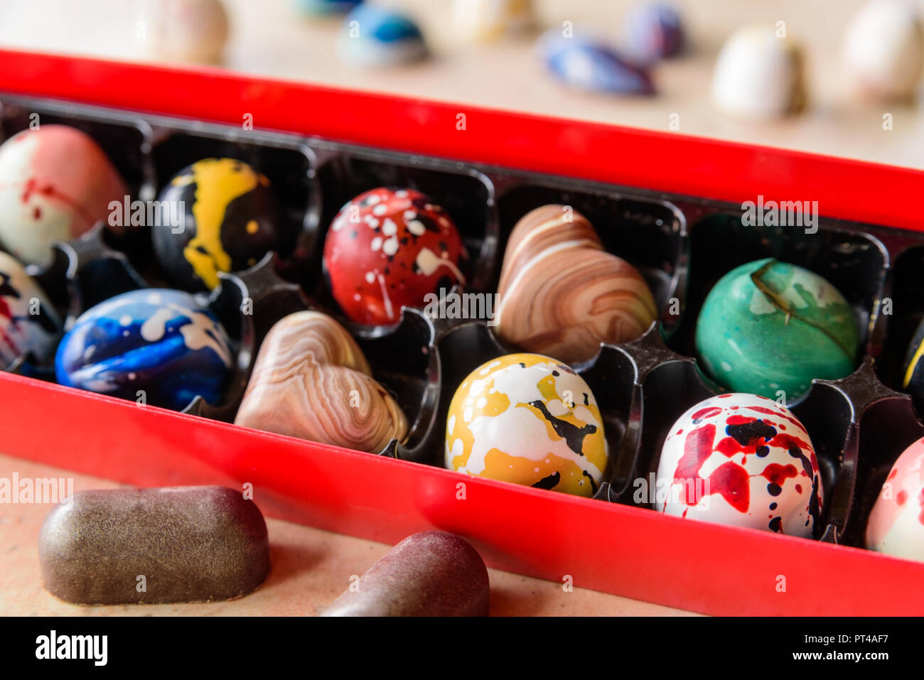 Red open box regalo con assortimento di cioccolato artigianale bomboni entrambi all'interno e al di fuori della casella. Due cuori di cioccolato all'interno della scatola. Foto Stock