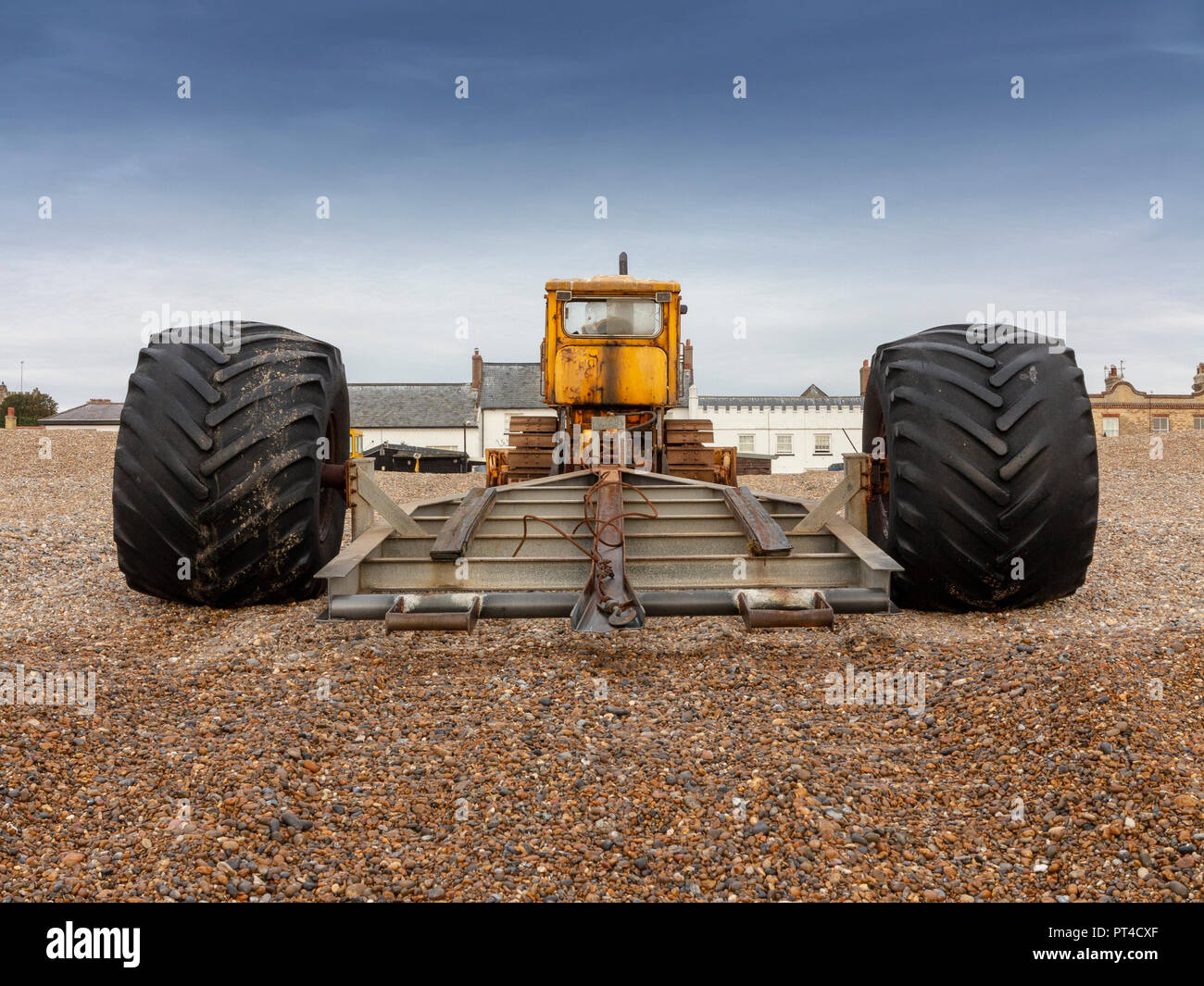 Bulldozer utilizzato come barca launcher parcheggiata su una spiaggia di ciottoli con edifici dietro Aldeburgh Suffolk Foto Stock