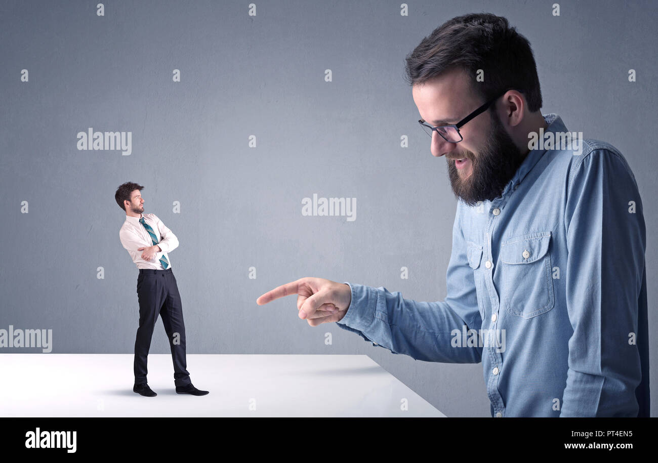 Giovane imprenditore professionale essendo arrabbiato con un altro imprenditore in miniatura Foto Stock