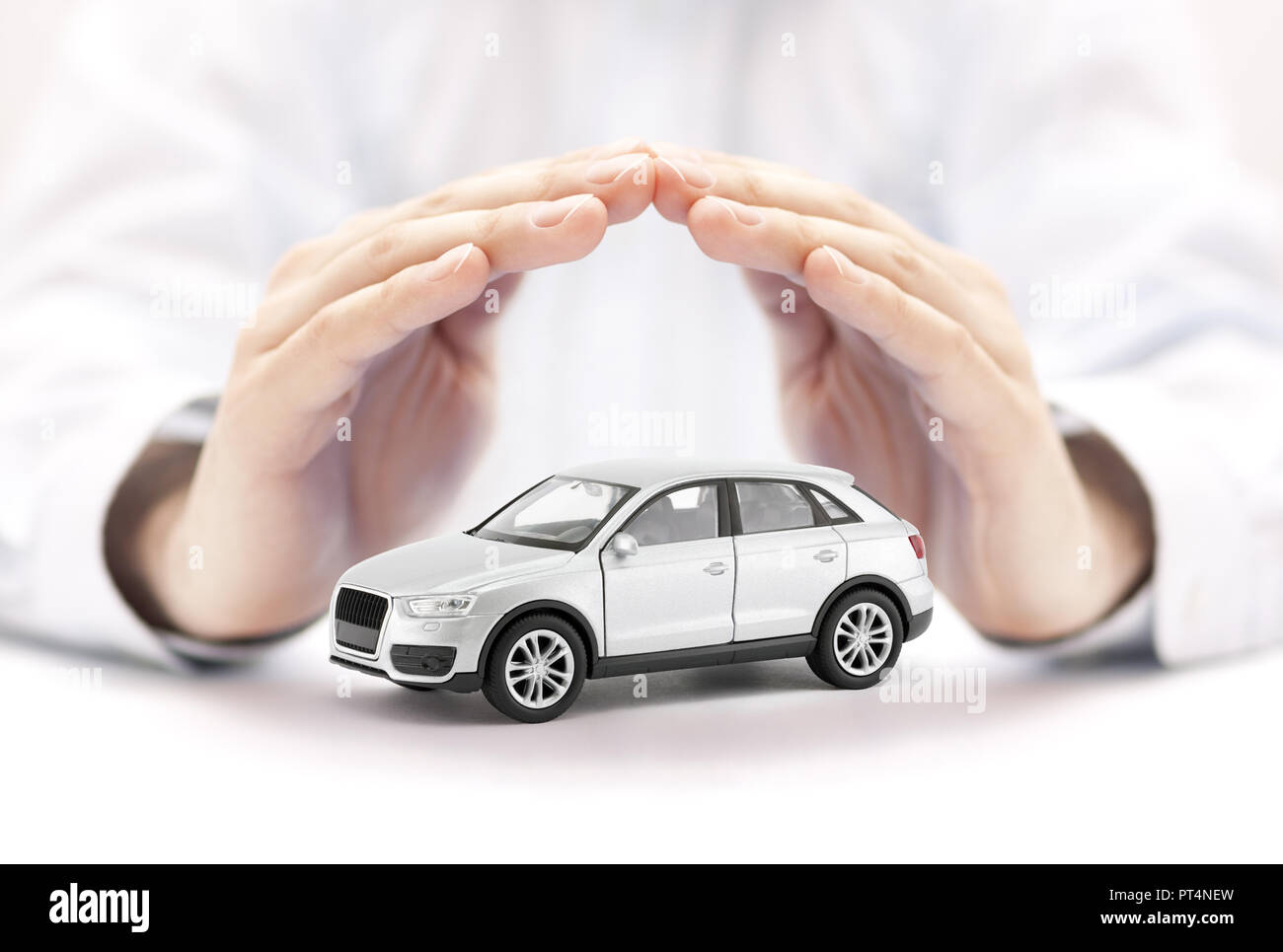 Assicurazione auto. Argento piccolo giocattolo auto coperti da mani Foto Stock