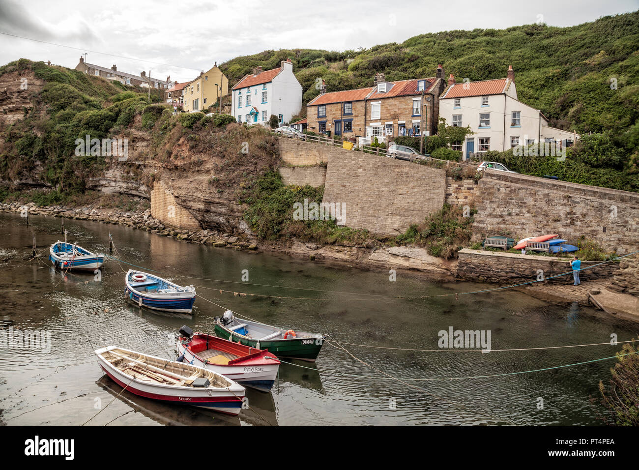 Barche ormeggiate nel fiume che sfocia nel mare di Staithes, vicino a Scarborough Foto Stock