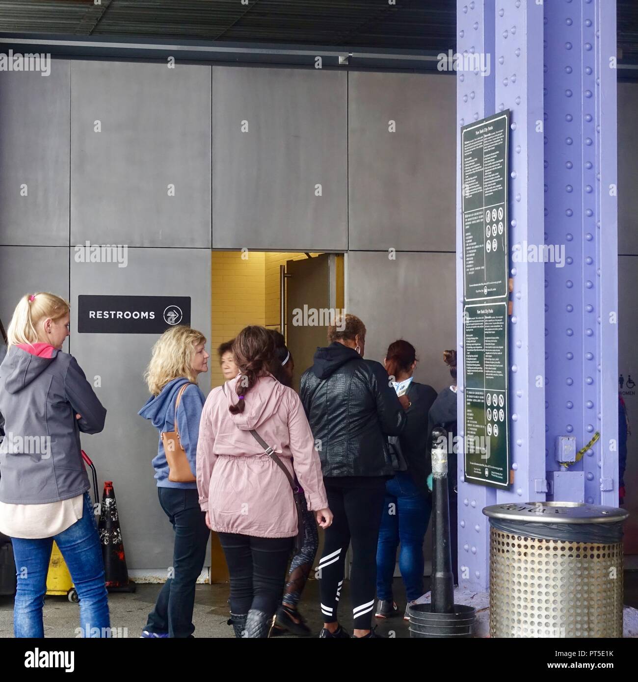 Le donne in piedi in una linea lunga al di fuori di un wc pubblico, con nessuna linea al di fuori dell'uomo. New York, NY. Foto Stock