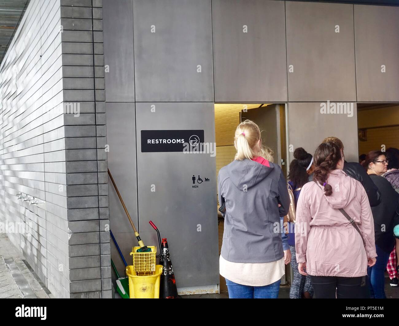 Le donne in piedi in una linea lunga al di fuori di un wc pubblico, con nessuna linea al di fuori dell'uomo. New York, NY. Foto Stock