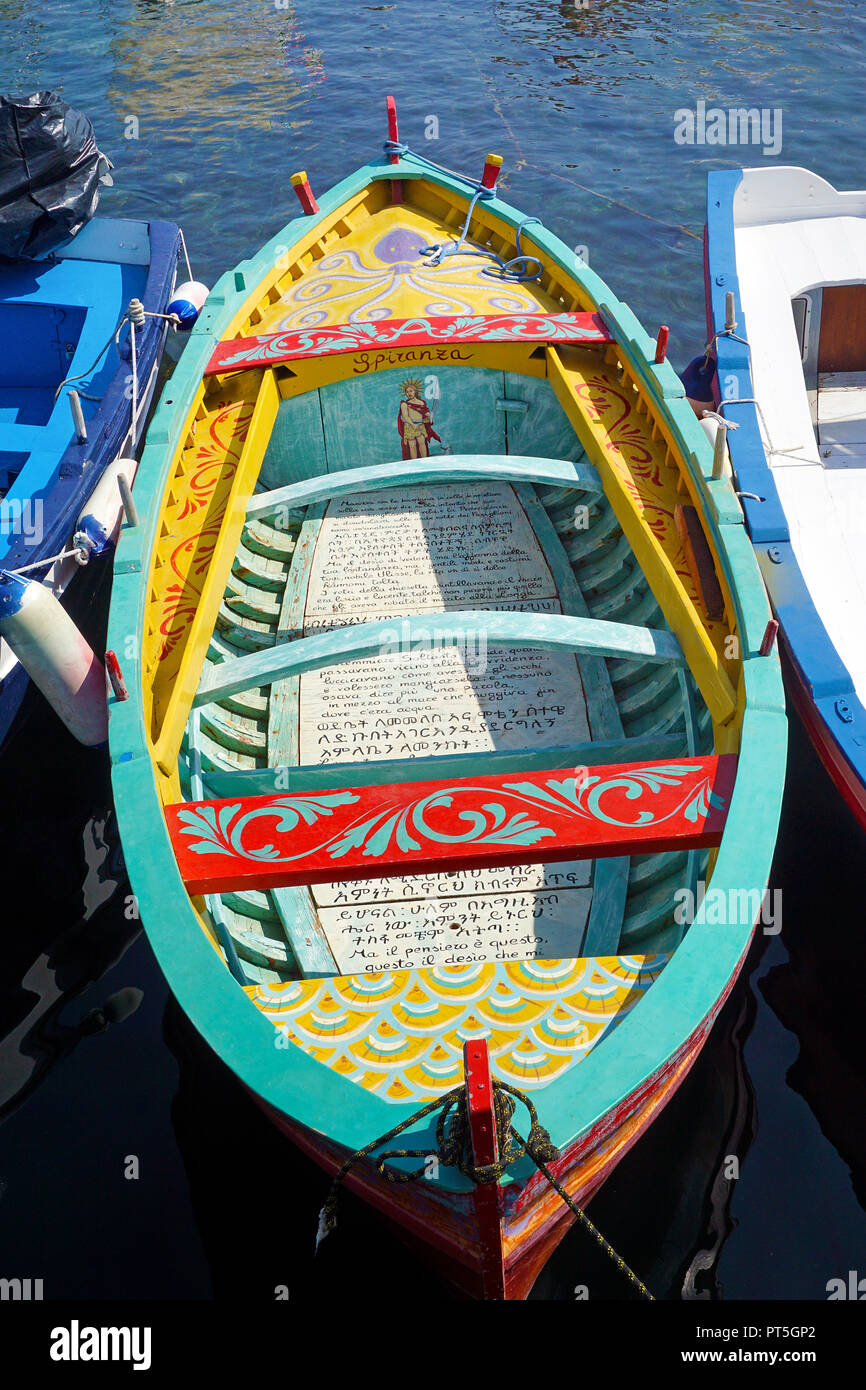 Verniciato colorato barca da pesca con testo religioso al porto del villaggio di pescatori di Aci Trezza, comune di Aci Castello, Catania, Sicilia, Italia Foto Stock