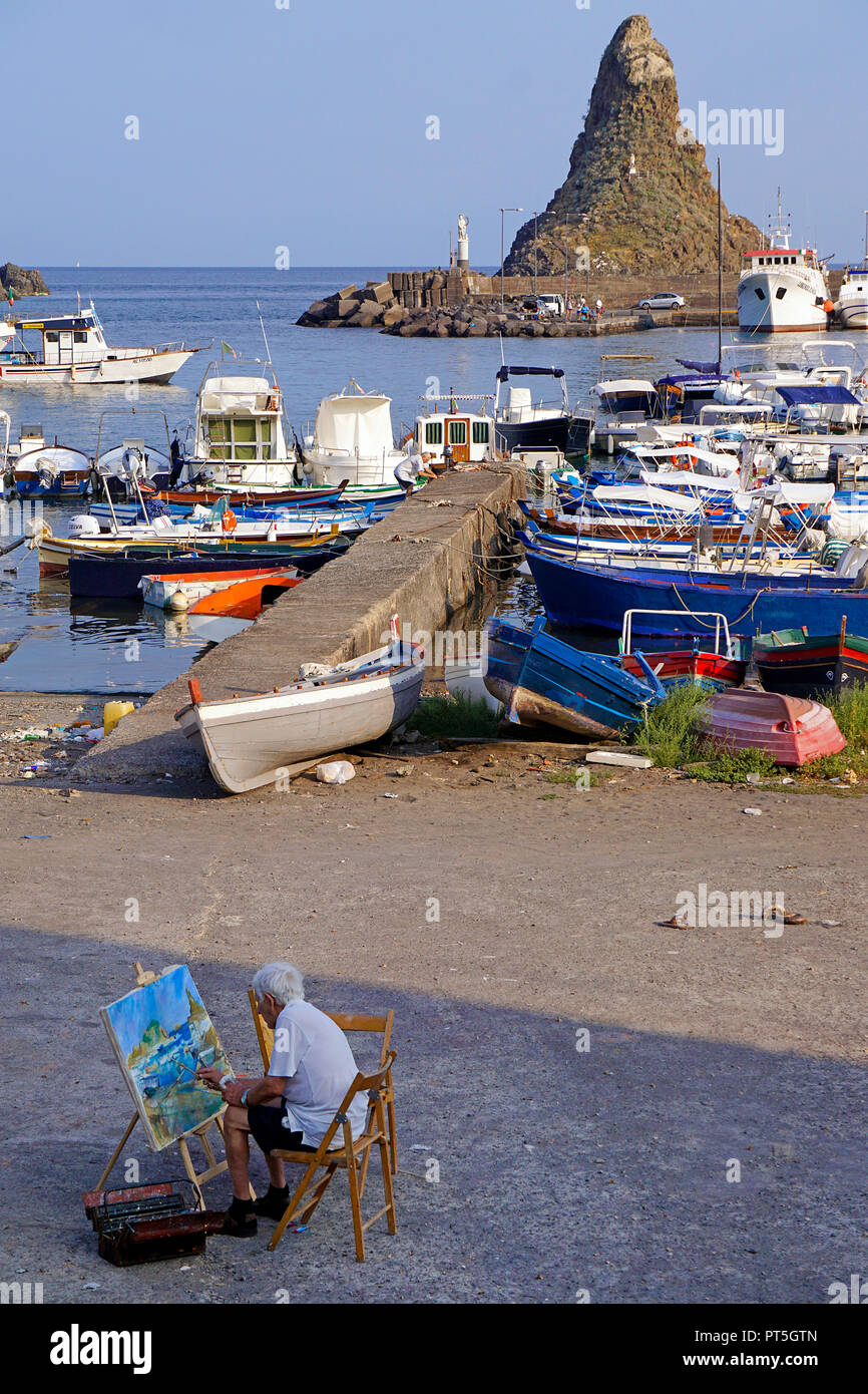 Pittore al porto del villaggio di pescatori di Aci Trezza, dietro il Faraglione grande, comune di Aci Castello, Catania, Sicilia, Italia Foto Stock