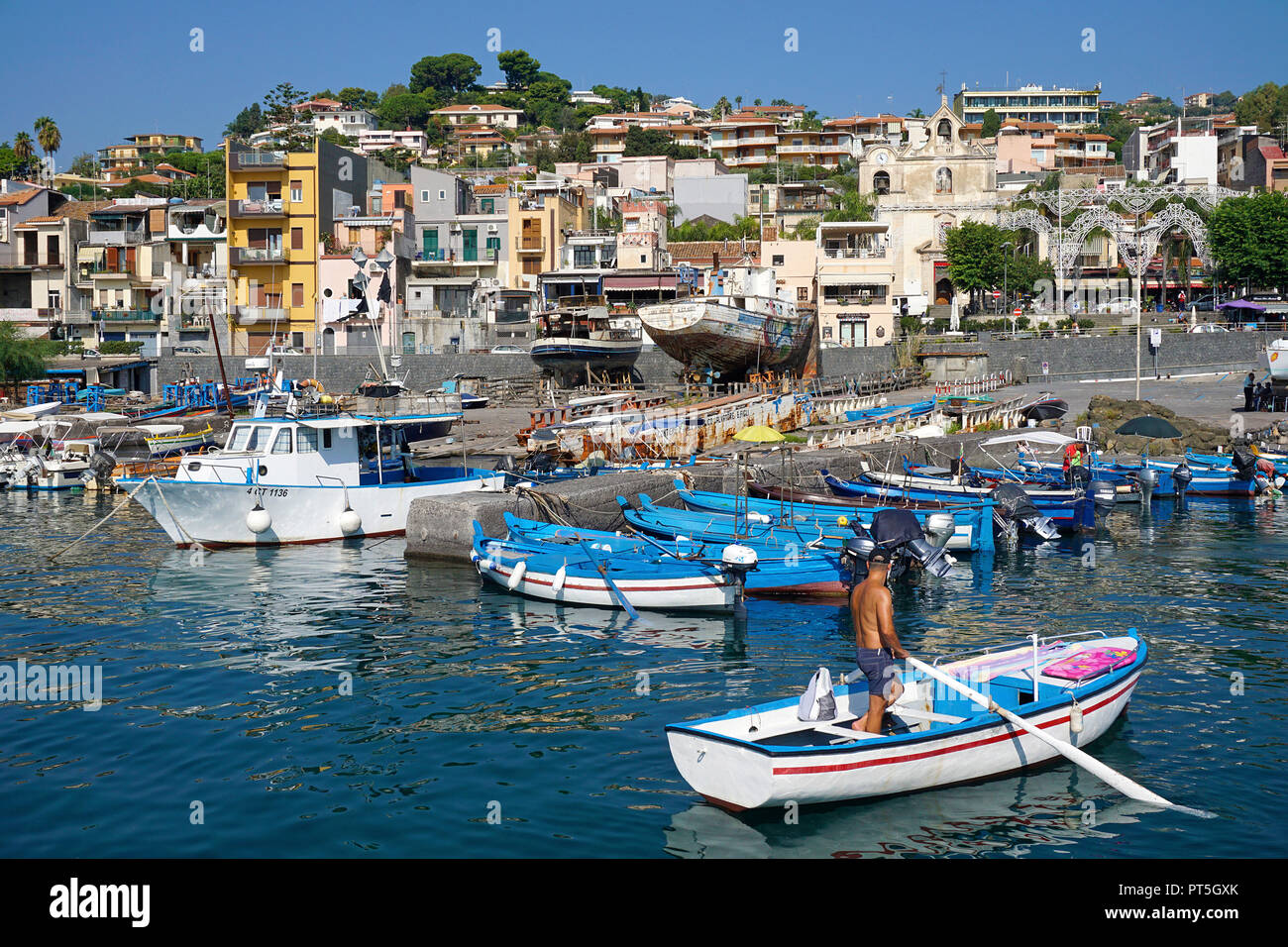 Pescatore con canotto a porto del villaggio di pescatori di Aci Trezza, comune di Aci Castello, Catania, Sicilia, Italia Foto Stock