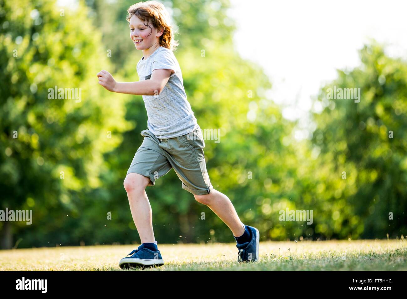 Ragazzo in esecuzione nel parco, sorridente. Foto Stock