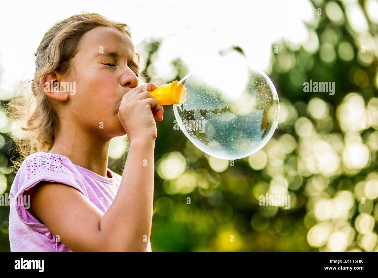 Ragazza a soffiare bolle con bolla di bacchetta magica nel parco. Foto Stock