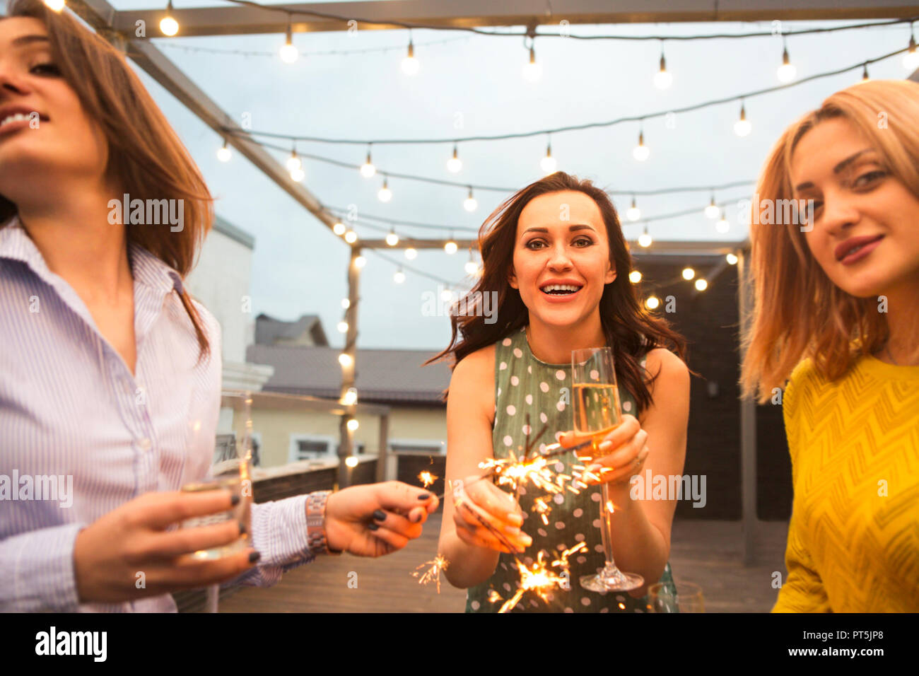 Un gruppo di ragazze che partying con flauti con vino frizzante e il Bengala fire divertirsi sulla parte Foto Stock