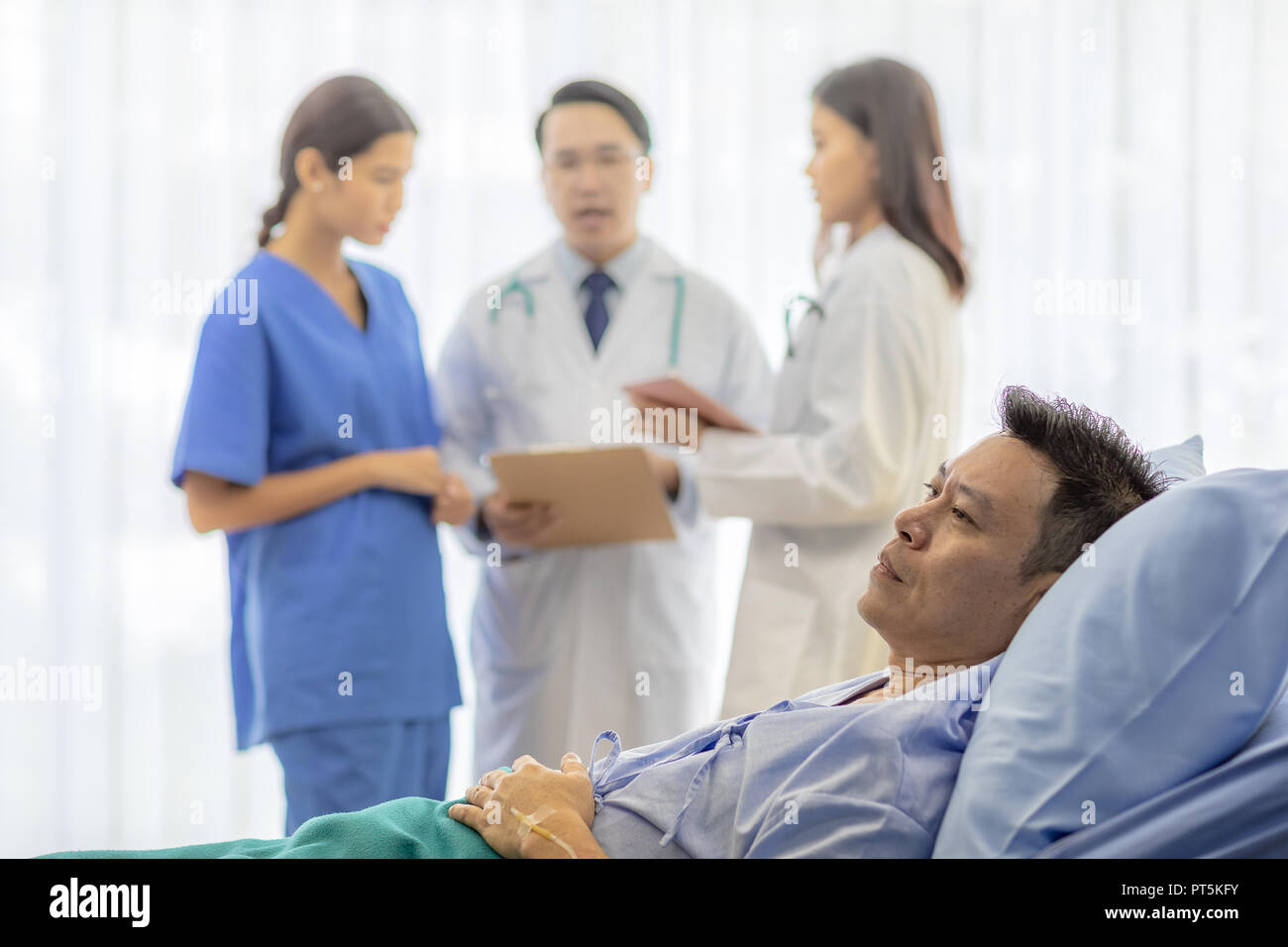 Preoccupato per il paziente nel letto con team di professionisti medici in background Foto Stock