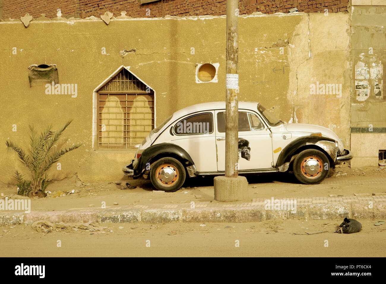 Vecchio bianco e nero Volkswagen maggiolino parcheggiato sul lato a piedi di una strada di Aswan, Egitto. Foto Stock