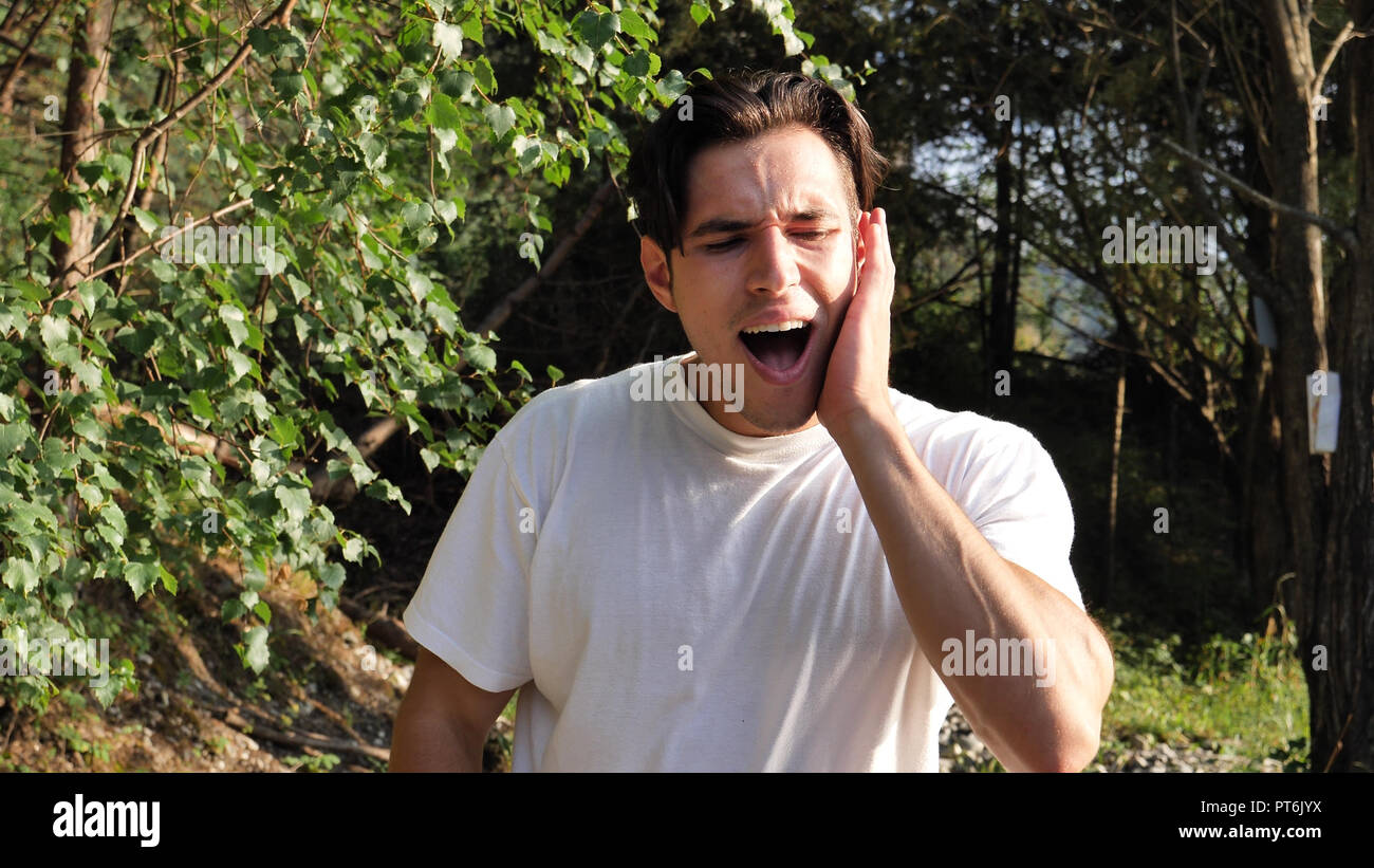 Giovane uomo nella natura che soffrono di mal di denti Foto Stock