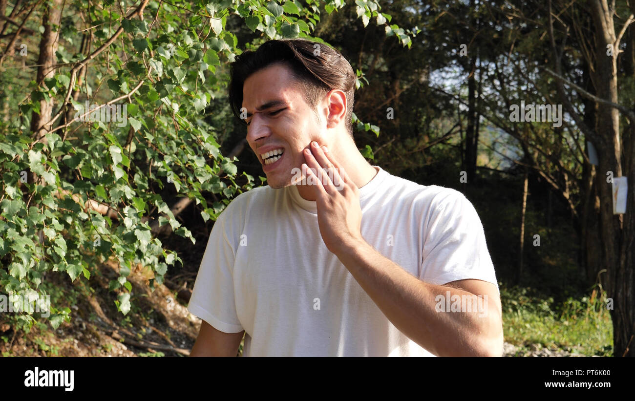 Giovane uomo nella natura che soffrono di mal di denti Foto Stock