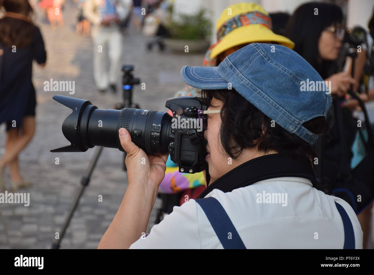 Donna cinese di scattare le foto con le sue telecamere sulla Tsim Sha Tsui promenade di Hong Kong, Cina Foto Stock