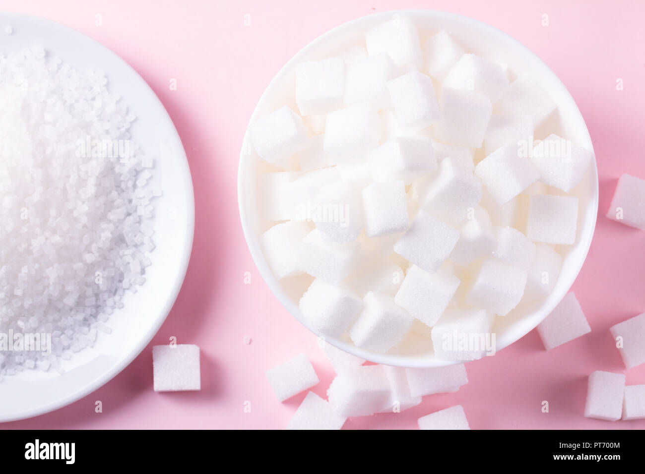 Lo zucchero in cubetti di cristallinità abd, piatto giaceva su sfondo rosa Foto Stock