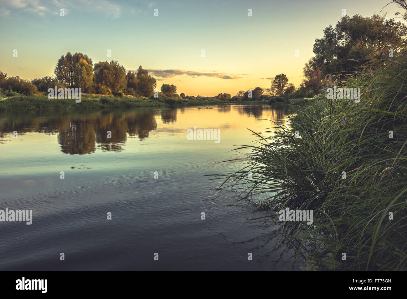 Stagione estiva campagna rustica fiume calmo paesaggio tramonto con cielo chiaro riflessioni riverbank in stile vintage Foto Stock