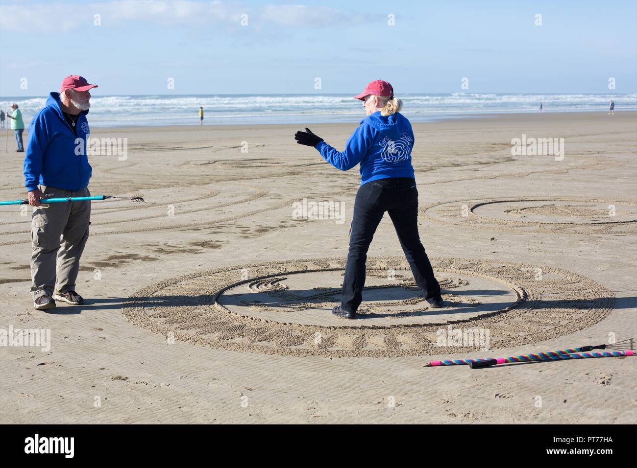 Sabbia artista Denny Dyke parlando ad un volontario che aiutano a creare un grande labirinto di sabbia ha progettato, a Heceta Beach in Firenze, Oregon, Stati Uniti d'America. Foto Stock